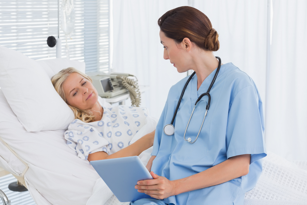 Doctor showing tablet to her patient in hospital room